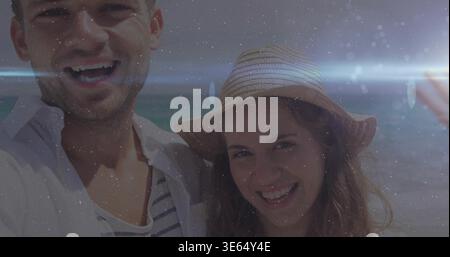 Laughing man in striped tee and woman in straw hat recording selfie at seaside, capturing memory Stock Photo