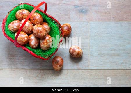 Traditional Easter eggs in basket on wooden background. Rustic composition with copy space, festive holiday concept. Stock Photo