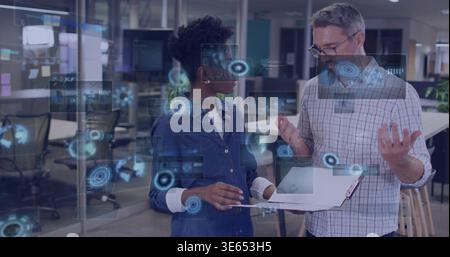 Discussing lead checked and developer denim in tech office with clipboard-laptop and AR overlays Stock Photo