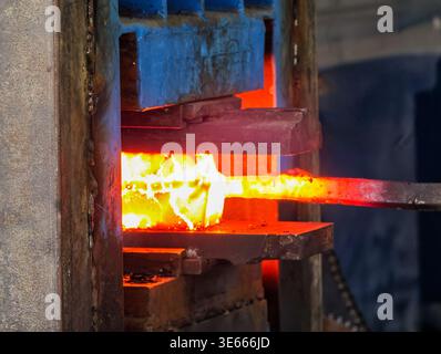 Heavy industrial forging: A hydraulic press shaping a red-hot block of incandescent steel. Stock Photo