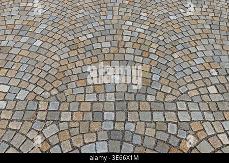 Close-up of curved cobblestone pavement pattern in neutral gray and beige tones, ideal as an abstract stone surface background or architectural textur Stock Photo