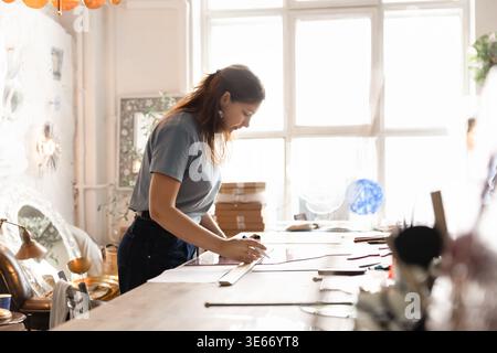 Female artist sketching on glass sheet in creative studio Stock Photo