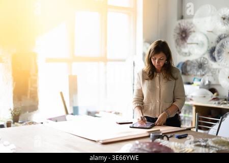 Female artist drawing on digital tablet in glass studio Stock Photo