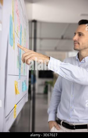 Pensive mid aged businessman selecting colored stick on scrum board Stock Photo