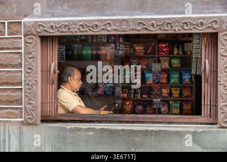 Smiling male shopkeeper sitting behind the counter in his shop in Jodhpur, India Stock Photo