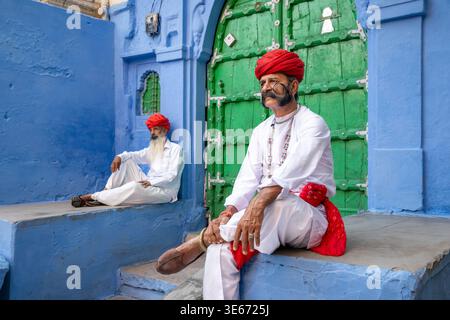 Two Rajasthani men wearing traditional white kurta and red turbans in the Blue City of Jodhpur, India Stock Photo