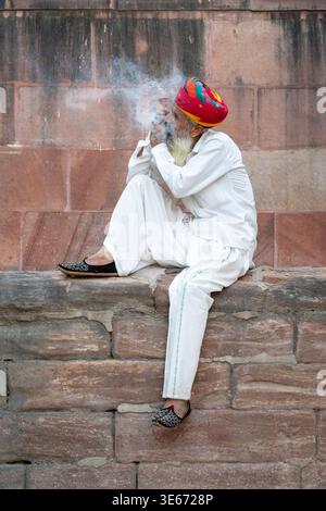 Portrait of an Indian man with a long beard and colorful turban smoking a tobacco pipe in Jodhpur, India Stock Photo