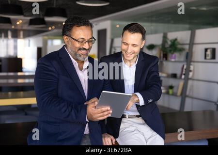 Two smiling business colleagues watching digital content on tablet Stock Photo