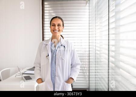 Smiling adult female doctor standing in clinic office Stock Photo