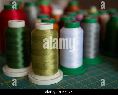 Colorful spools of sewing and embroidery thread arranged on a cutting mat, selective focus. The vibrant threads showcase a variety of textures and hue Stock Photo