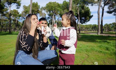 Happy family spending leisure time together in a park, blowing soap bubbles Stock Photo