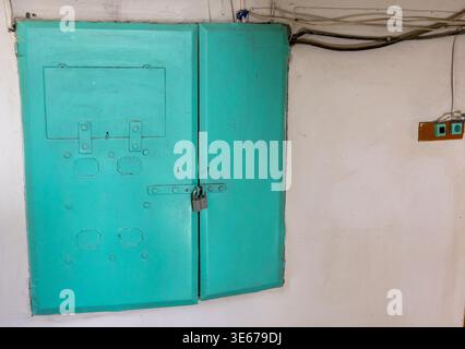 an electrical panel in a building with painted metal doors in an old multi-story building Stock Photo