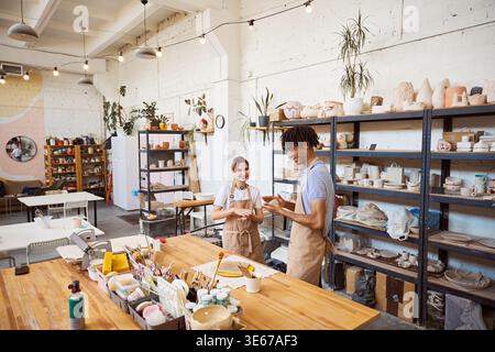Young adults creating pottery together in studio, daytime Stock Photo