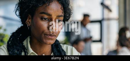 Focused female professional analyzing building layouts in open workspace Stock Photo
