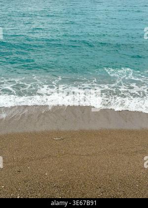Minimalist overhead view of sea foam on sandy pebble beach Stock Photo