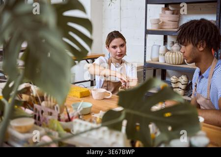 Young woman and man engaged in pottery making in studio Stock Photo