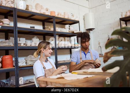 Young adults engaged in pottery at creative studio during day Stock Photo