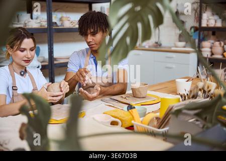 Young adults creating pottery in a bright studio Stock Photo