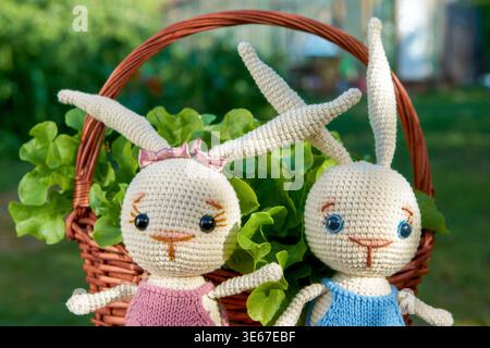 Toy bunnies in a basket with salad on a Sunny summer day Stock Photo