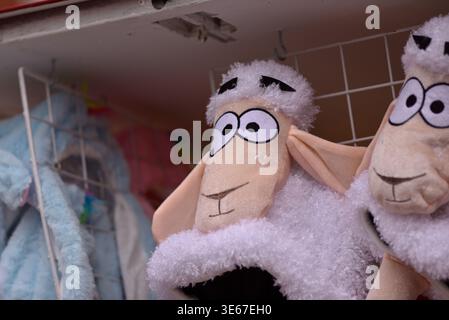 Close-up of two plush sheep toys with big cartoon eyes hanging on a wire rack Stock Photo