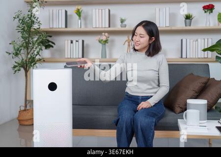 Woman using a remote to operate an air purifier Stock Photo