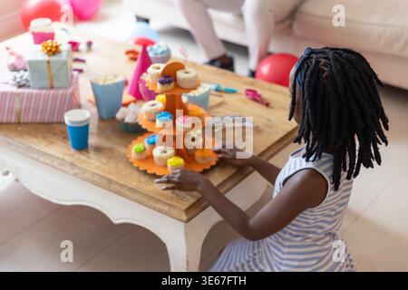 3-tier orange cupcake stand holding frosted cupcakes on coffee table at home, gifts nearby Stock Photo