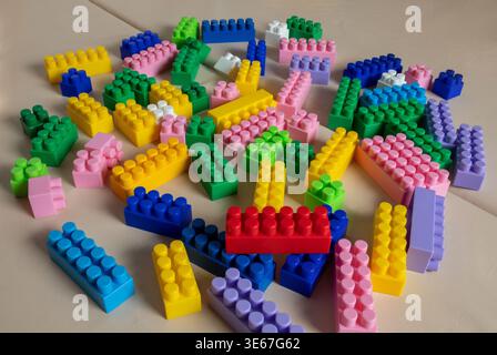 High angle view of a pile of various colorful plastic building bricks on a white floor or table Stock Photo