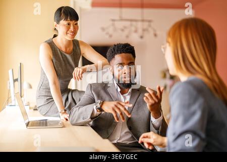 Group of professional coworkers collaborating and discussing company's growth during corporate meeting Stock Photo