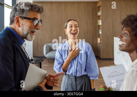 Cheerful group of business people laughing and talking while collaborating on ideas during office meeting Stock Photo