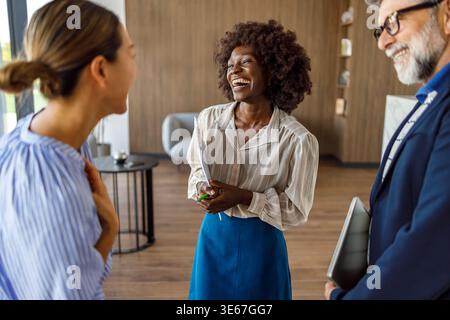 Happy business professionals laughing while sharing ideas and collaborating during team meeting in modern office Stock Photo