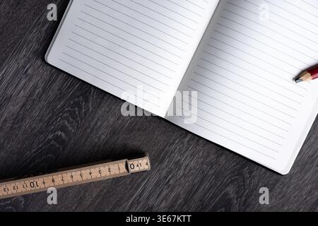 Open lined notebook with pencil and ruler on wooden desk. Minimal workspace with copy space, concept of writing, planning, studying and measuring. Stock Photo