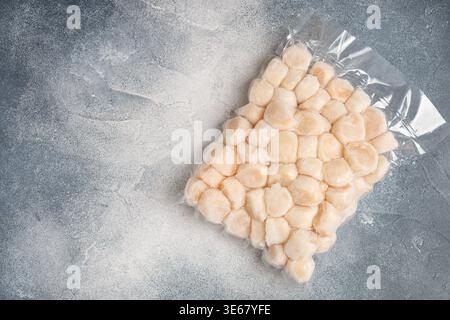 Frozen meat scallop in vacuum package. Raw delicatessen seafood. Concrete or stone background. Selective focus, top view and copy space Stock Photo