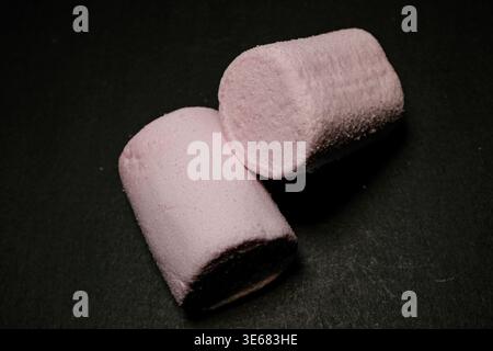 Two pink marshmallows on a dark surface, soft texture visible, studio-lit close-up Stock Photo