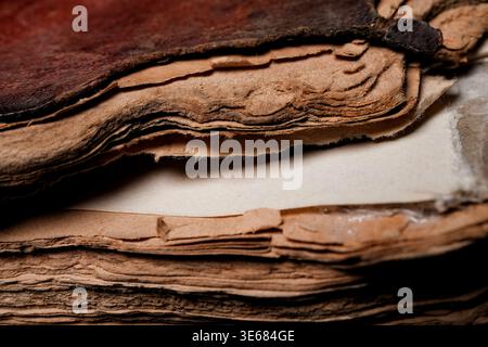 Close-up of aged, layered, torn paper edges and a worn leather cover, warm tones and high texture detail Stock Photo