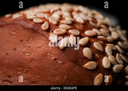 Close-up of a sesame-seed topped bread crust with golden brown texture and scattered sesame seeds, shallow depth of field Stock Photo