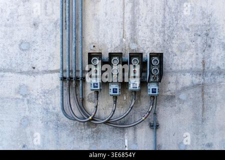 A series of outdoor local control stations (LCS) with push buttons and indicators mounted on a weathered concrete wall. The image shows industrial ele Stock Photo