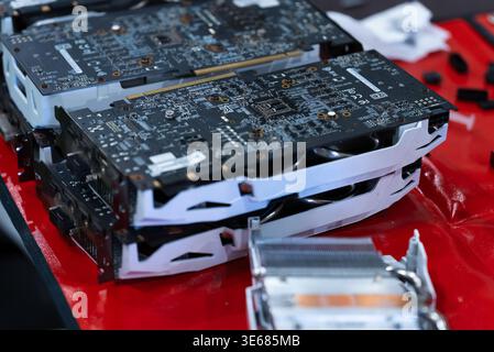 video card with a gray metal radiator and cooling pipes lies stacked on a red surface Stock Photo