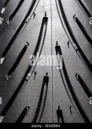 High-resolution macro shot of a brand-new automotive tire tread, featuring the intricate rubber texture, drainage grooves, and manufacturing vent spew Stock Photo