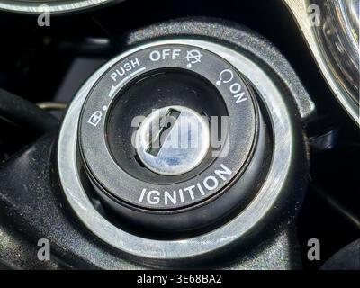 Close up of a modern motorcycle ignition switch and keyhole slot. Detailed macro shot showing lock, push, on, and off steering lock markings. Ideal fo Stock Photo