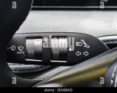 Close up of a multi-function steering column stalk in a modern car. Control dials for automatic windshield wipers, headlights, and turn signals are vi Stock Photo