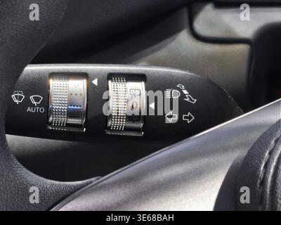 Close up of a multi-function steering column stalk in a modern car. Control dials for automatic windshield wipers, headlights, and turn signals are vi Stock Photo
