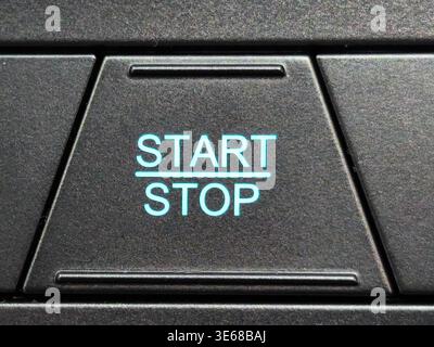 Close up of a modern engine start stop button on a car dashboard. Features electronic ignition system symbols for fuel efficiency and smart technology Stock Photo