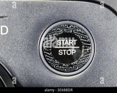 Close up of a modern engine start stop button on a car dashboard. Features electronic ignition system symbols for fuel efficiency and smart technology Stock Photo