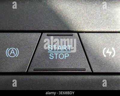 Close up of a modern engine start stop button on a car dashboard. Features electronic ignition system symbols for fuel efficiency and smart technology Stock Photo