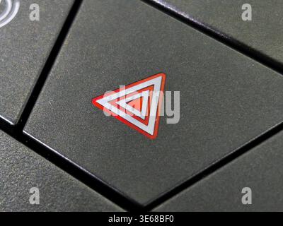 Close up of a red triangle hazard warning flasher button on a modern car dashboard. This essential safety feature is used to alert other drivers durin Stock Photo