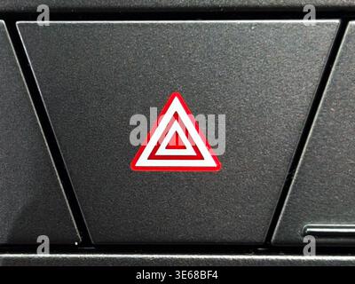 Close up of a red triangle hazard warning flasher button on a modern car dashboard. This essential safety feature is used to alert other drivers durin Stock Photo