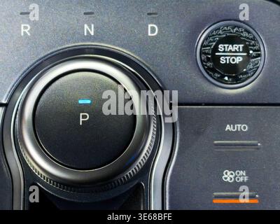 Close up of a sleek rotary gear shifter in a modern car interior. Showcases P, R, N, and D positions with an electronic parking indicator on a texture Stock Photo