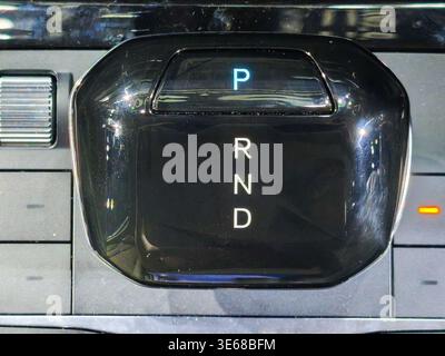 Close up of a sleek automatic gear shifter in a modern luxury car interior. Features PRND letters with park light illuminated on a glossy black surfac Stock Photo