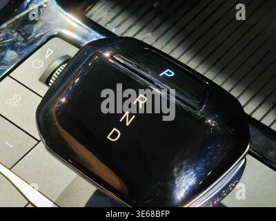 Close up of a sleek automatic gear shifter in a modern luxury car interior. Features PRND letters with park light illuminated on a glossy black surfac Stock Photo