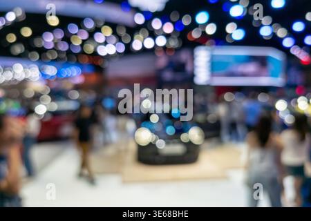 Abstract defocused shot of a car show featuring a vehicle silhouette and colorful bokeh lights in an exhibition hall. Ideal for automotive marketing, Stock Photo